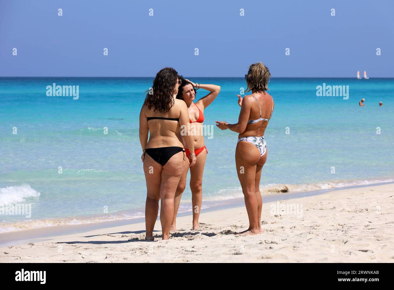 Drei Frauen im Bikini, die am tropischen Strand reden. Seeküste, Touristenresort auf Karibikinsel Stockfoto