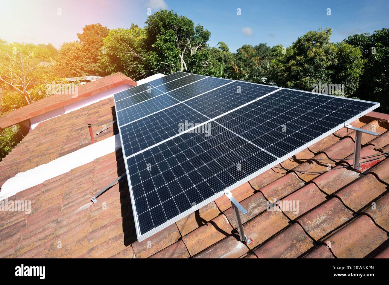 Haus Solaranlage auf Lehmdach auf grünen Bäumen Hintergrund Stockfoto