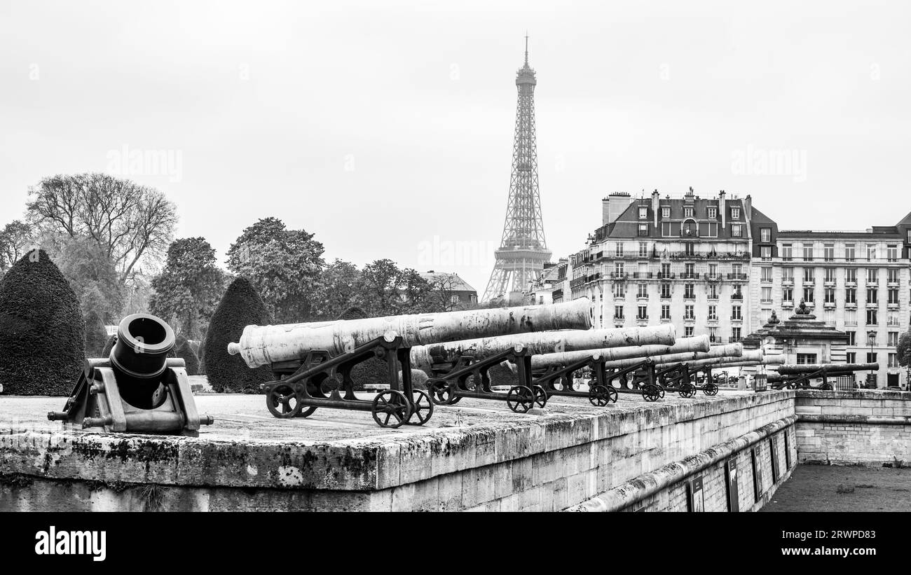Historische Kanonen in Les Invalides und pariser Stadtbild mit Eiffelturm, Paris, Frankreich. Schwarzweißfotografie. Schwarzweißfotografie. Stockfoto
