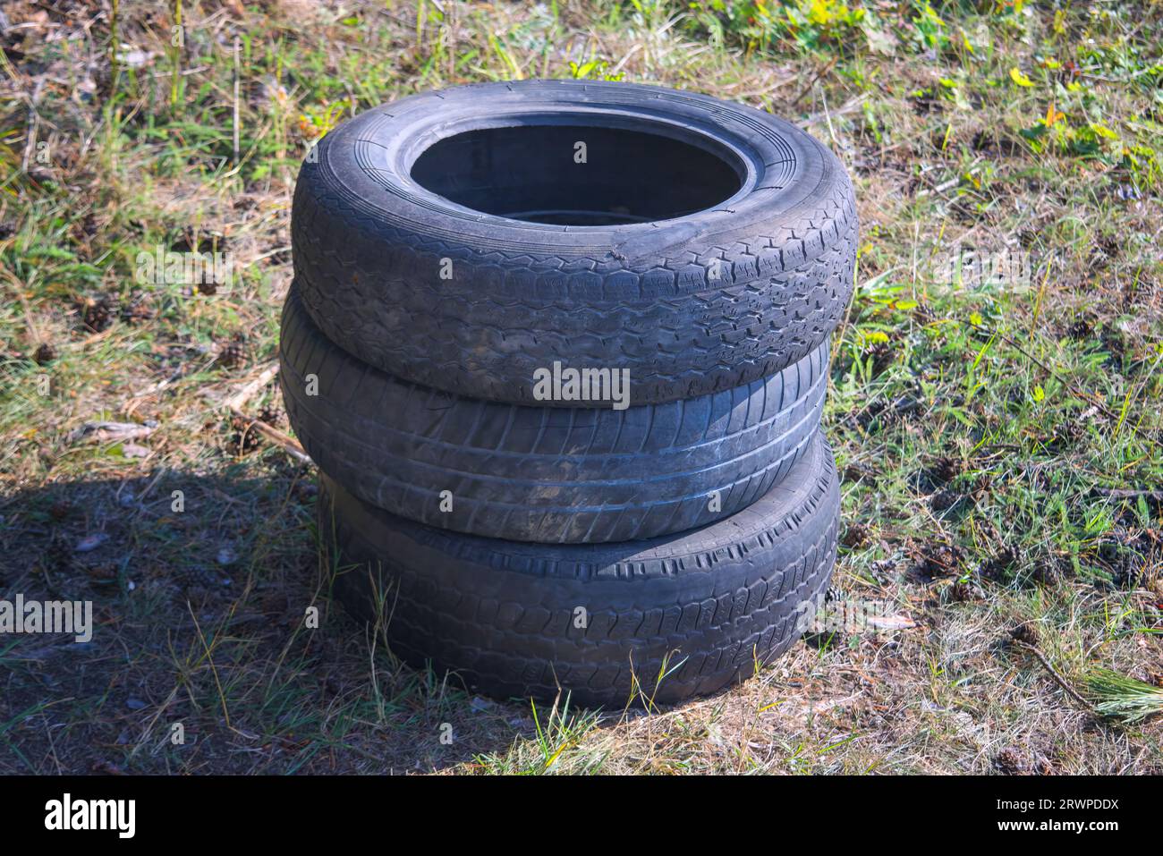 Alte Autoreifen, die in einem Stapel gefaltet sind, liegen auf dem Gras. Stockfoto