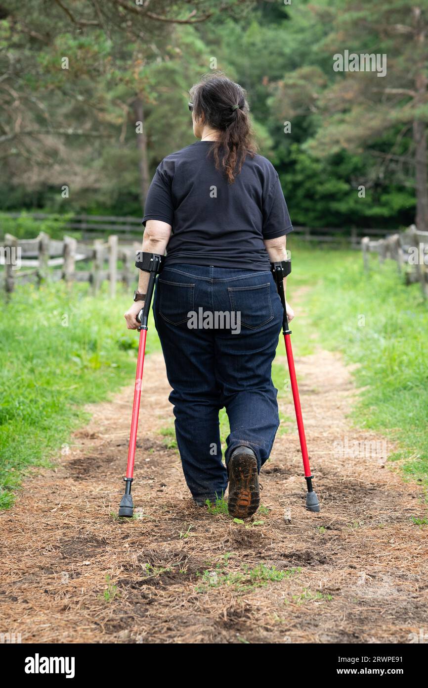 Eine behinderte Frau mit Unterarmkrücken, die auf einem Pfad spaziert Stockfoto