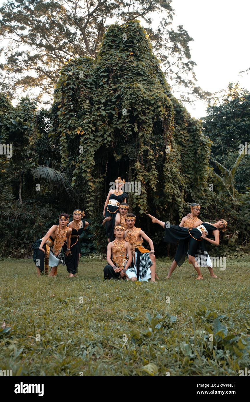 Indonesische Tänzerinnen posieren mit ihren Körpern, während sie vor dem Wald ein traditionelles goldenes Kostüm von Javanern tragen Stockfoto