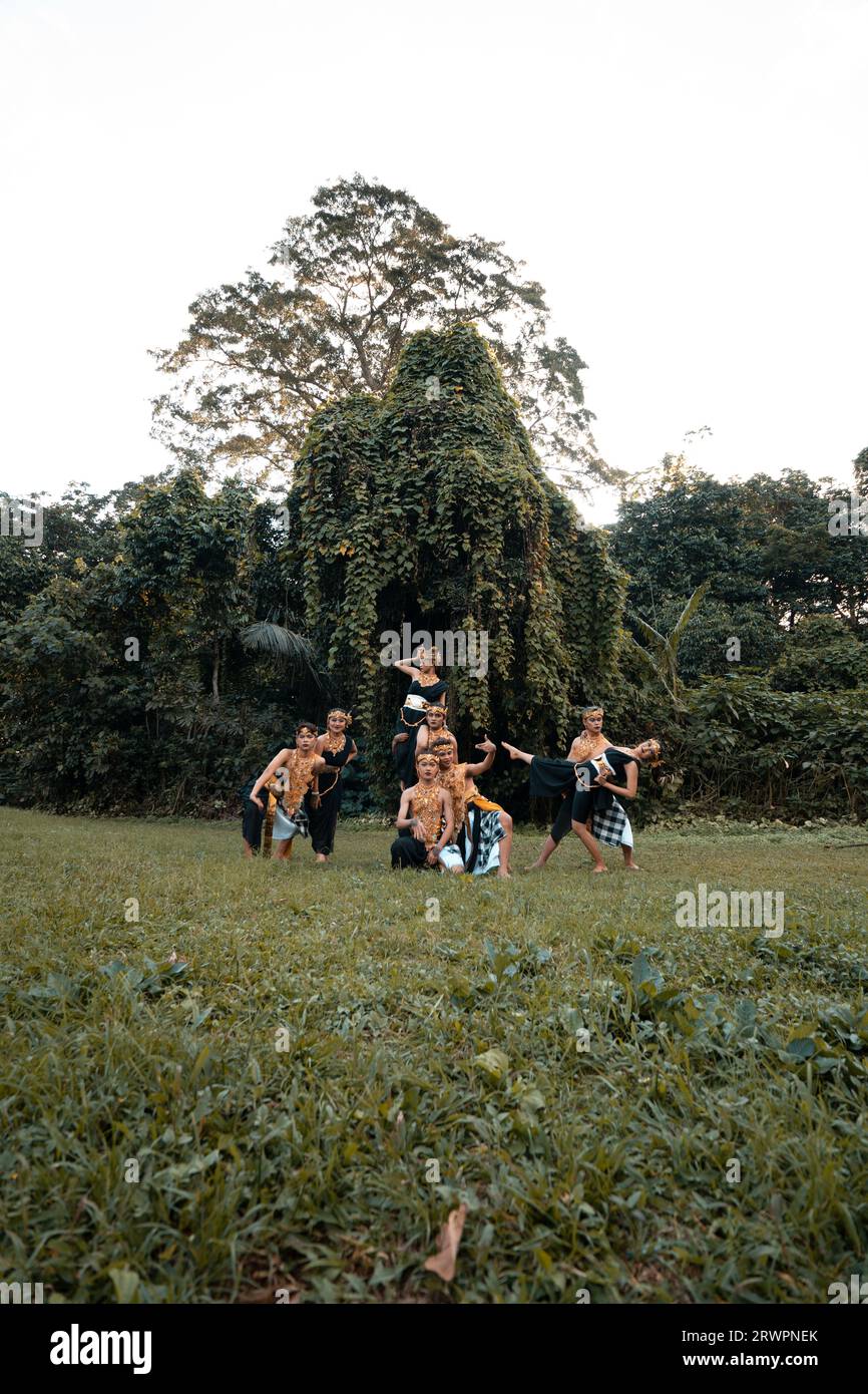 Indonesische Tänzerinnen posieren mit ihren Körpern, während sie vor dem Wald ein traditionelles goldenes Kostüm von Javanern tragen Stockfoto
