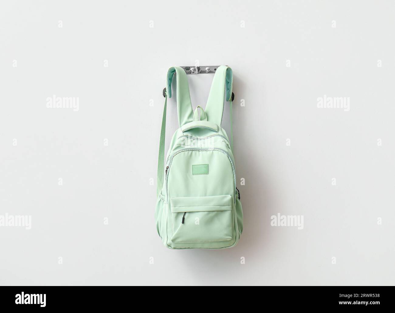 Stylischer Schulrucksack, der an einer hellen Wand hängt Stockfoto