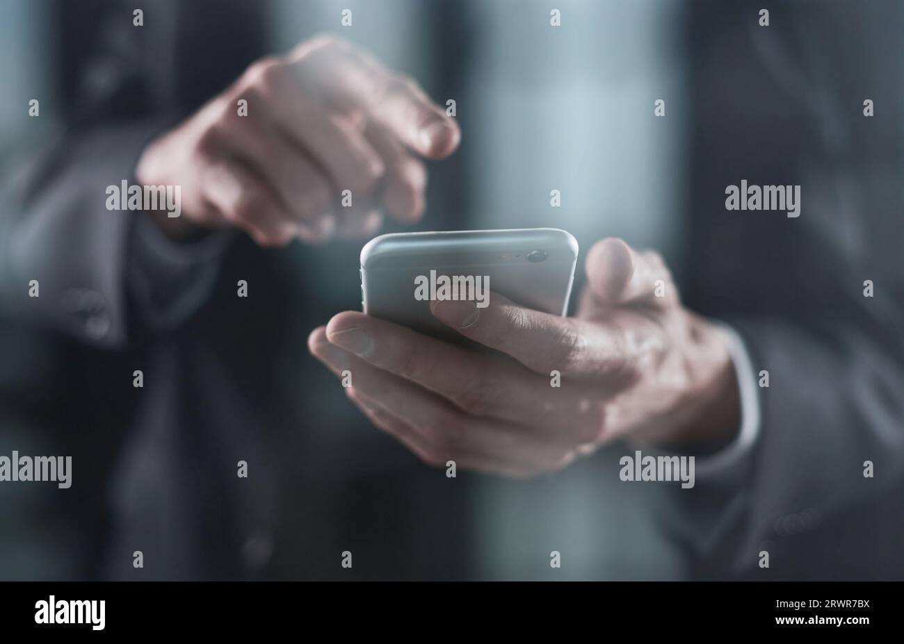 Smartphone in den Händen eines jungen Mannes auf schwarzem Hintergrund. Schreiben Sie Text mit den Fingern. Stockfoto