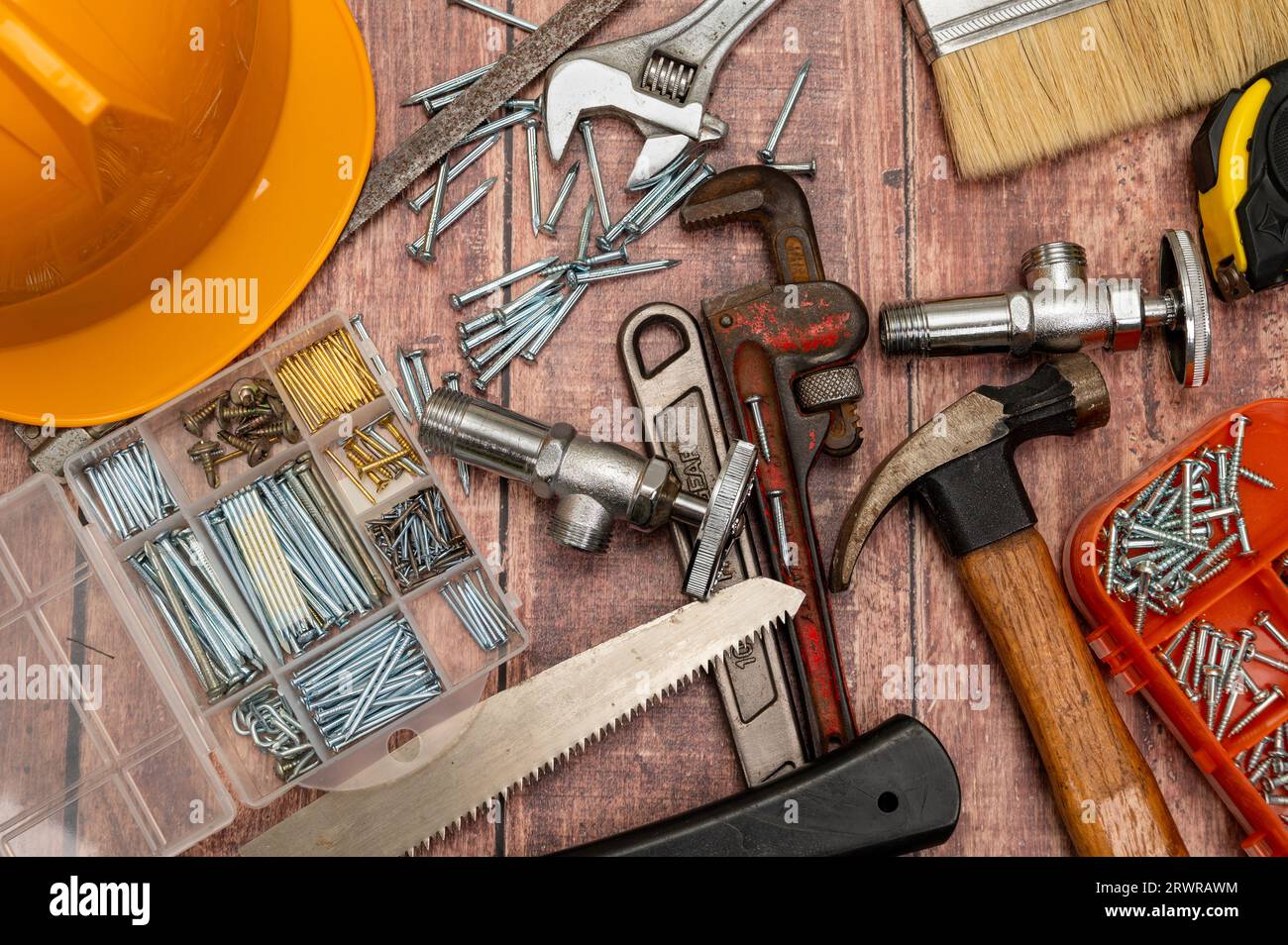 Auf einem Holzbrett werden eine Vielzahl von Werkzeugen, die für die Reparatur zu Hause benötigt werden, unregelmäßig platziert. Stockfoto