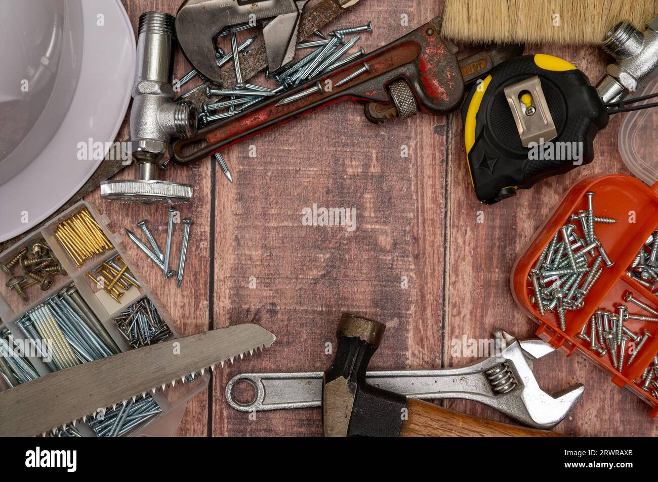 Auf einem Holzbrett werden eine Vielzahl von Werkzeugen, die für die Reparatur zu Hause benötigt werden, unregelmäßig platziert. Stockfoto