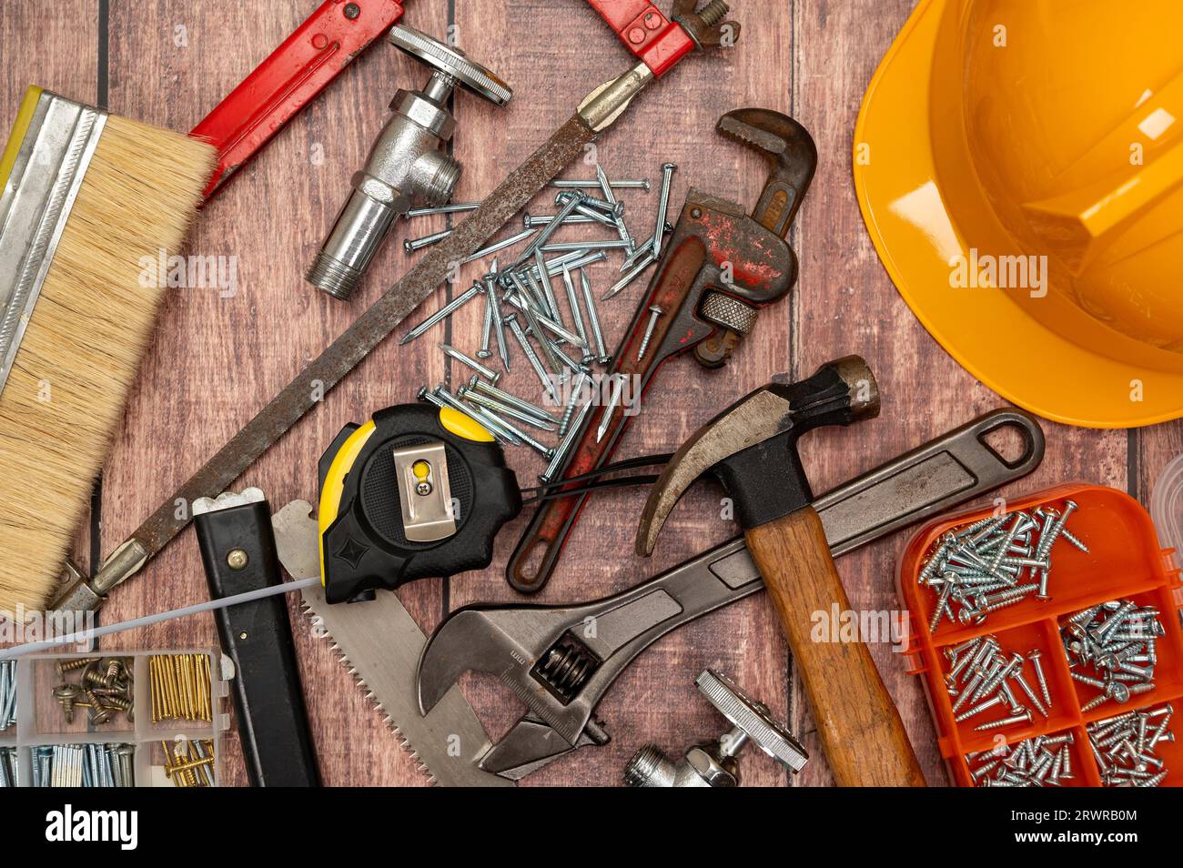 Auf einem Holzbrett werden eine Vielzahl von Werkzeugen, die für die Reparatur zu Hause benötigt werden, unregelmäßig platziert. Stockfoto