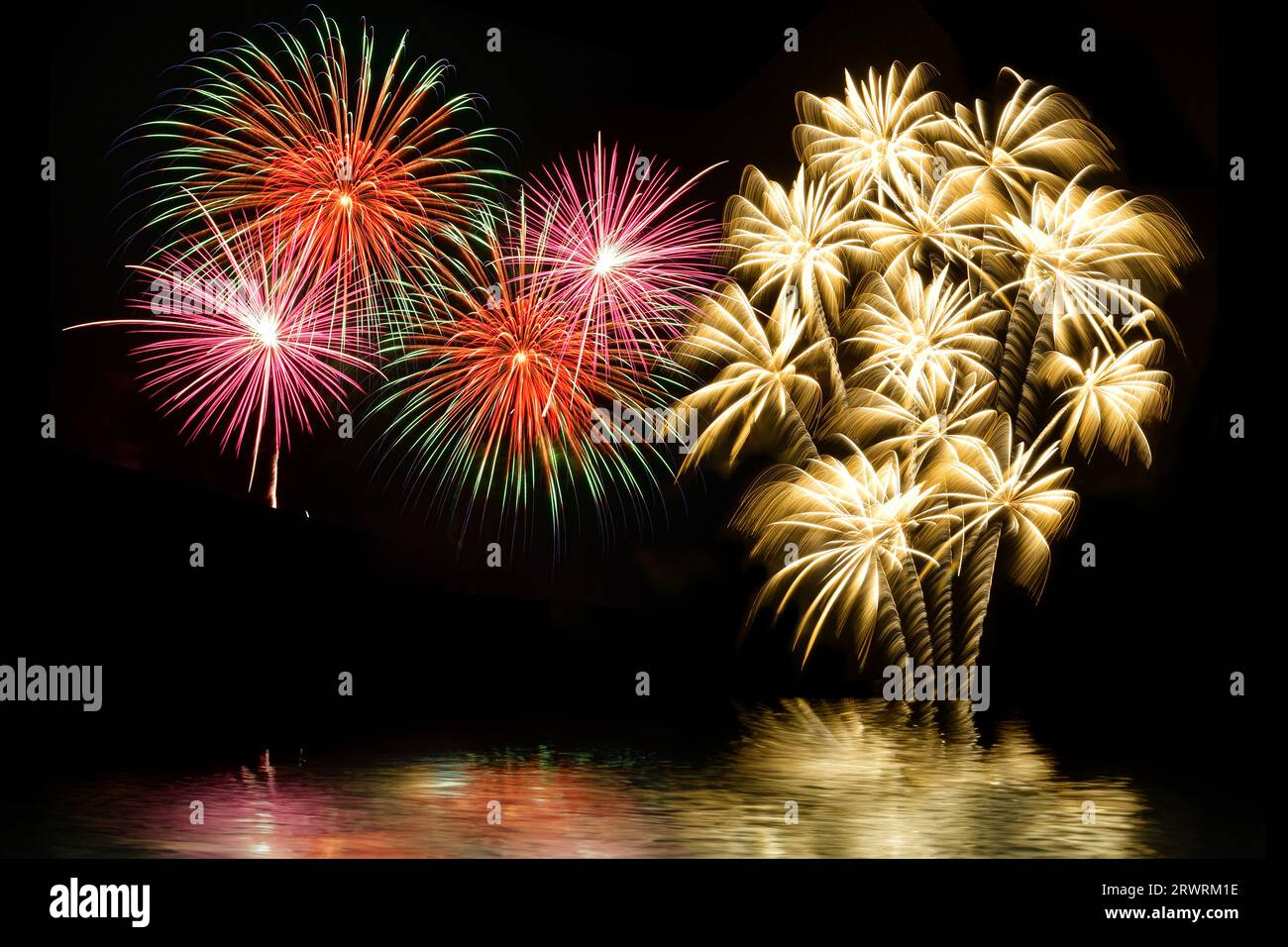 Buntes Feuerwerk und der Hintergrund des Nachthimmels mit Reflexion auf dem Wasser. Stockfoto