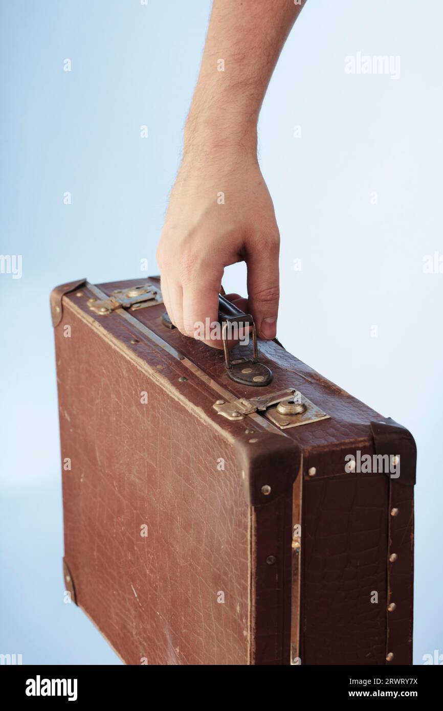 Eine Hand mit einem alten braunen Koffer Stockfoto