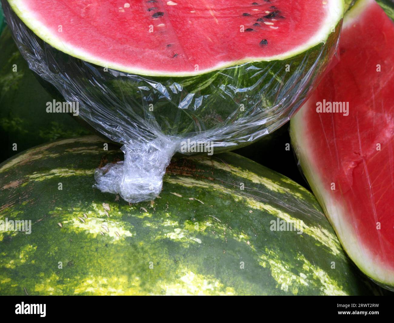 Wassermelonen, zwei Hälften, umwickelt in Klebefolie, ausgeschnitten Stockfoto