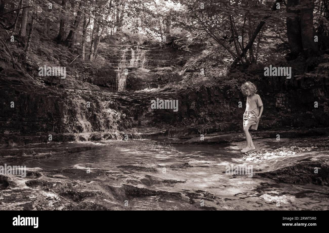 Sepia-farbenes Mädchen spielt am Taugl-Ufer am Wald Wasser Zauber Weg bei Hintersee, Salzkammergut, Land Salzburg, Österreich, Europa Stockfoto