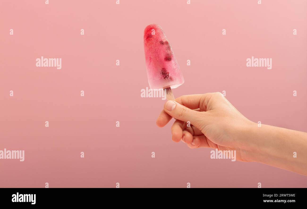 Die Frau hält einen Eiskegel auf rosafarbenem Hintergrund. . Hochwertige Fotos Stockfoto
