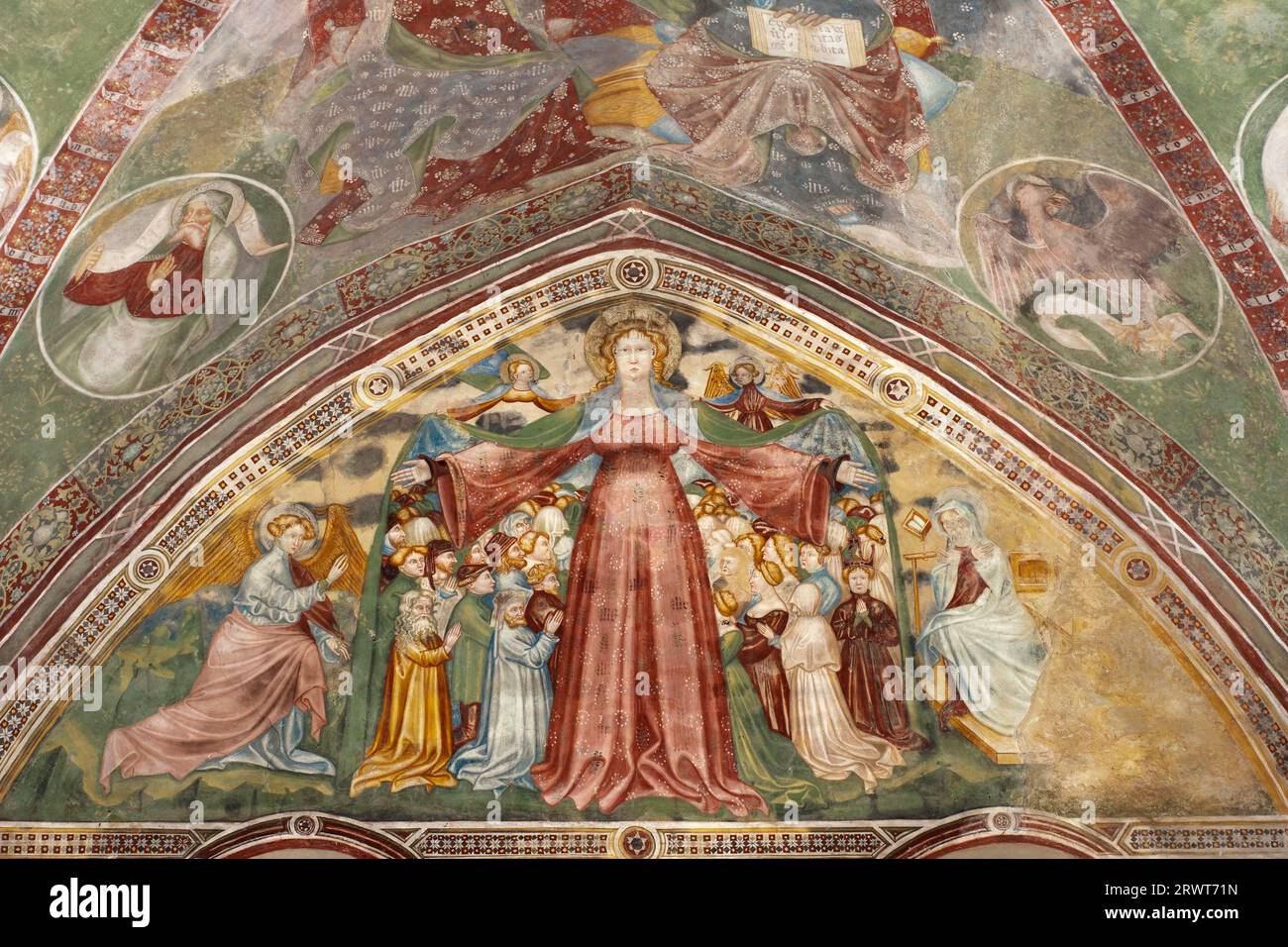 Fresko einer Madonna der Barmherzigkeit, die die verschiedenen Sozialgüter unter ihrem Mantel schützt, die Maestreo di Santa Maria in Wolkenstein in der Kirche Santa Stockfoto