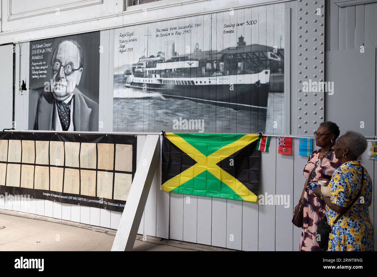 Ausstellung zum Windrush Day am Fährhafen Tilbury Docks, mit Jamaika-Flagge und Bildern des Architekten Sir Edwin Cooper und des 1933 erschienenen Schiffes Royal Eagle Stockfoto