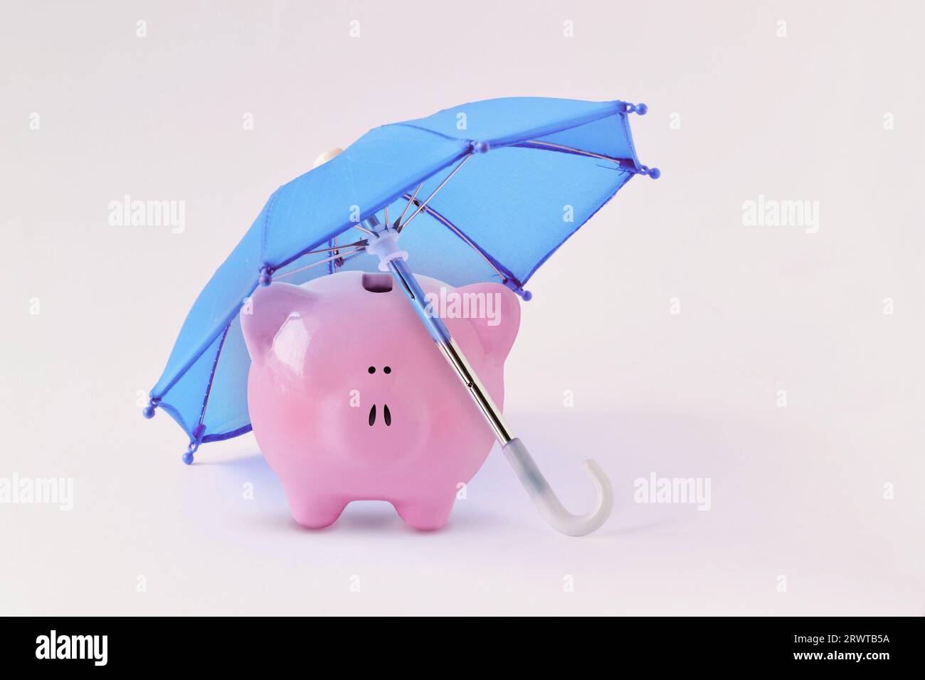Schweinebank unter blauem Schirm - Konzept von Geldschutz und Finanzsicherheit Stockfoto