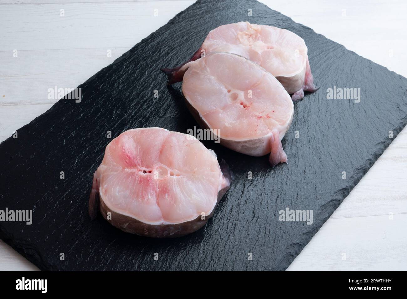 Scheiben frischer Meeraal auf einem schwarzen Brett. Stockfoto