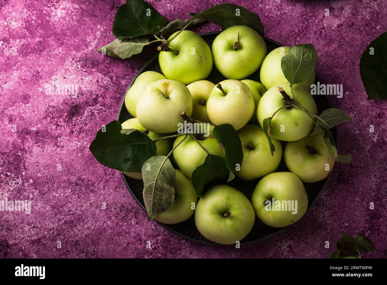 Frischer, reifer grüner Apfel auf violettem Hintergrund. Stockfoto