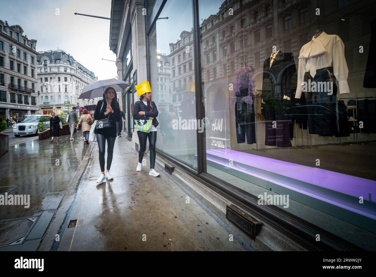 LONDON, 19. SEPTEMBER 2023: Shopper in der Regent Street sind im Regen gefangen, einer mit einer Tasche auf dem Kopf Stockfoto
