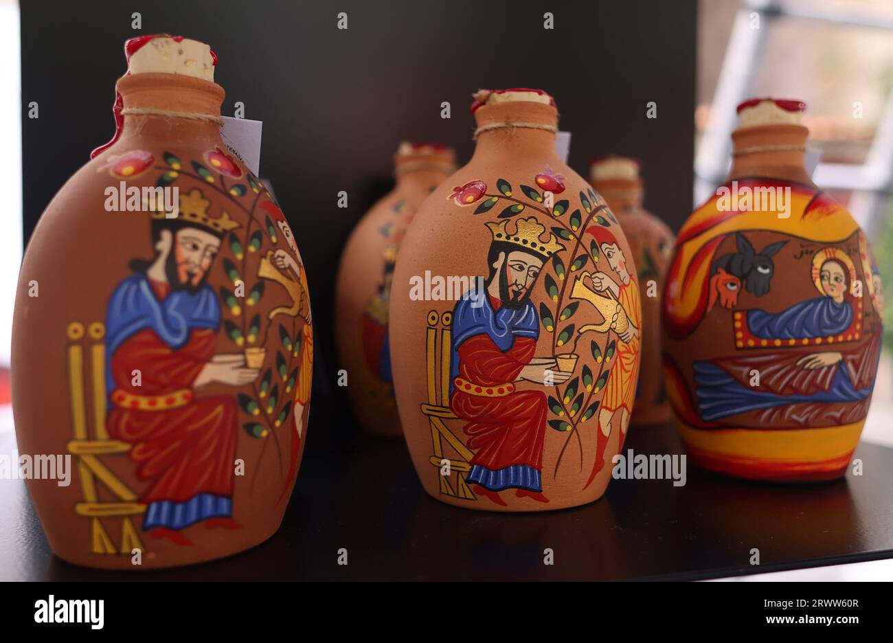 Eine Gruppe von drei handbemalten Glasflaschen in verschiedenen Farben, Größen und Designs werden nebeneinander auf einer glatten Holzoberfläche angezeigt Stockfoto