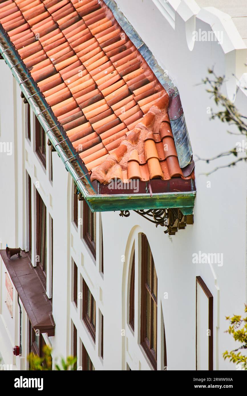Orangefarbene Tonfliesen auf Dachmarkisen mit grünen Regenrinnen auf weißem Gebäude Stockfoto