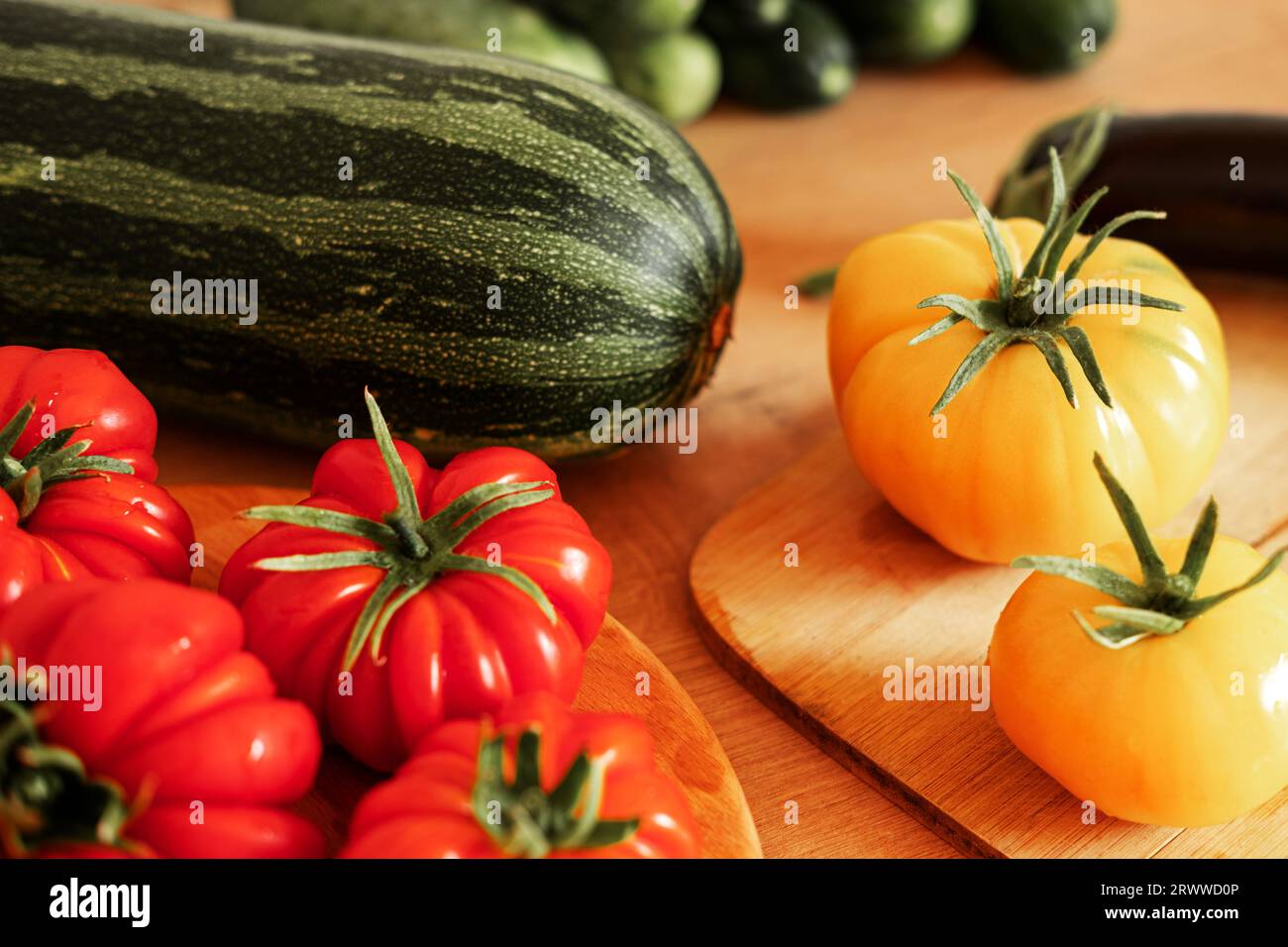 Frische reife große Tomaten, Auberginen, Gemüse auf einem Küchenarbeitsplatz aus Holz. Hintergrund vieler Rohgemüse. Tomaten, Gurken. Herd zu Hause macht eine Stunde Stockfoto