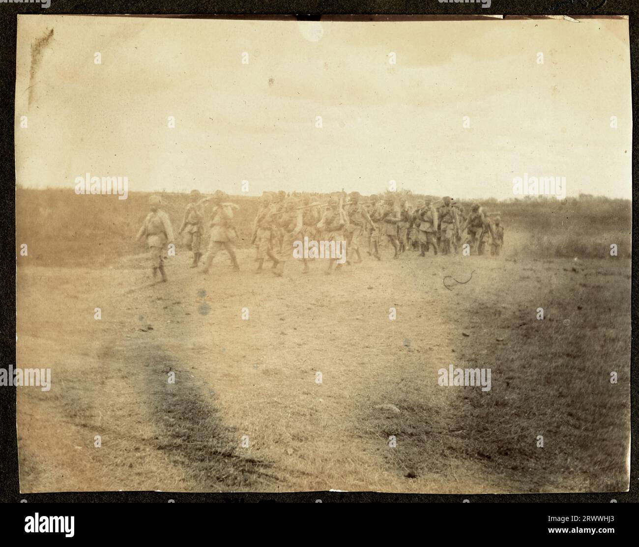Eine Gruppe von Kikuyu Dorfbewohnern führt einen traditionellen Tanz an einer unbefestigten Kreuzung mit Hügeln hinter sich auf. Originaltitel: Wakikuyu Dance. Stockfoto