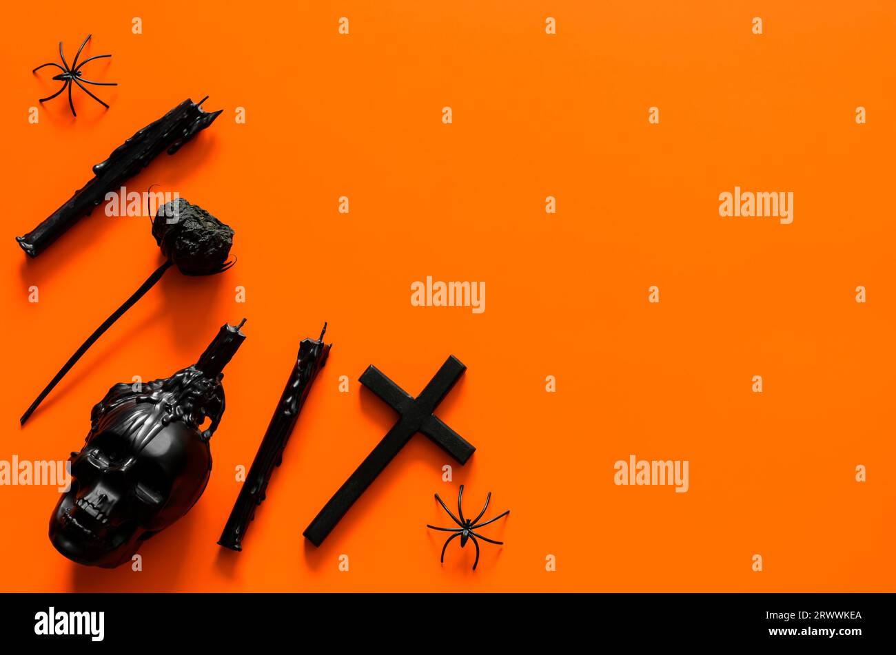 Schwarzes Dokorationszubehör auf orangefarbenem Hintergrund. Halloween-Party-Konzept. Stockfoto