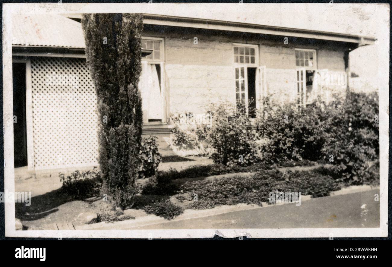 Blick auf einen großen, aus Stein gebauten Bungalow, der von den Gärten aus abgebildet ist, mit ordentlich angelegten Sträuchern und Blumenbeeten. Originalhandschrift: My Home in East Africa später Handschrift: Police Depot NBI 1923. Stockfoto