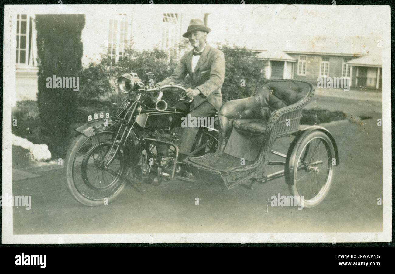 Bertie Rand sitzt auf einem Motorrad mit Beiwagen und gepolstertem Korbsessel. Er parkt vor dem Bungalow im Kolonialstil, der auf anderen Fotos als sein Zuhause, das Polizeidepot von Nairobi, identifiziert wurde. Spätere Handschriftenunterschrift: 1919. Stockfoto