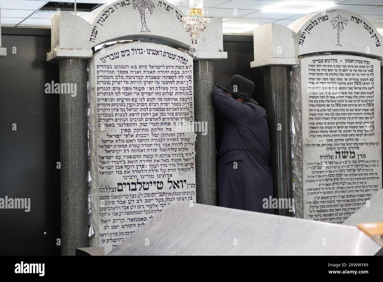 Ein orthodoxer jüdischer Mann betet neben den Grabsteinen der letzten beiden Satmarer Großrabbiner. Auf dem Old Satmar Cemetery in Kiryas Joel, Orange Cty, NY Stockfoto