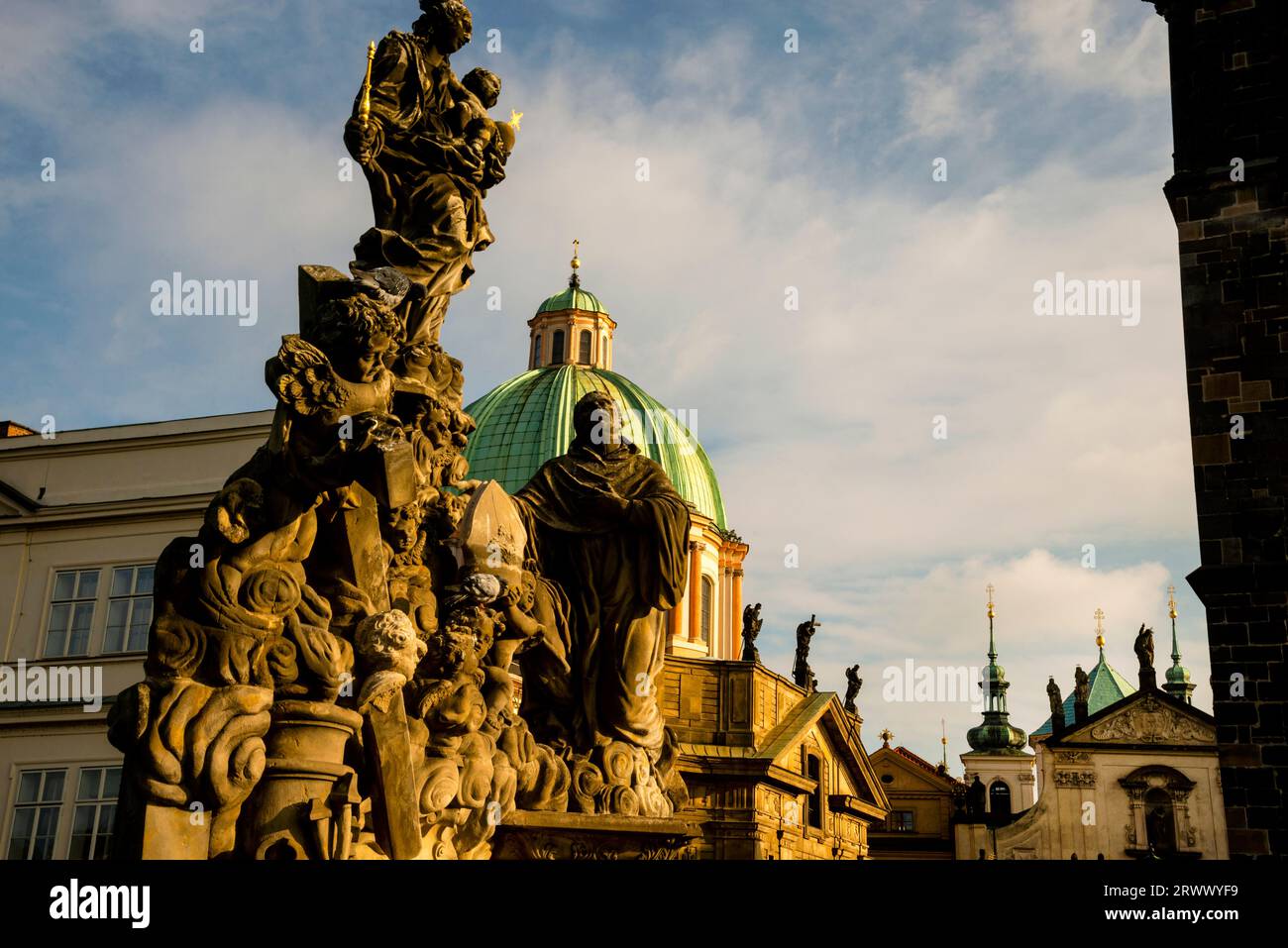 Barocke Kuppel von St.. Franz von Assisi in Prag und die Statue der Madonna und des Heiligen Bernhard auf der Karlsbrücke. Stockfoto