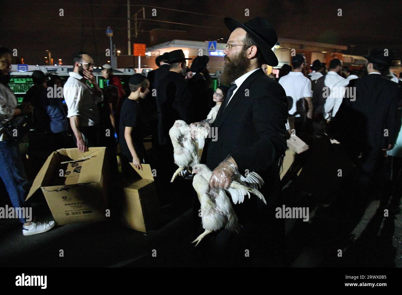 (230921) -- BNEI BRAK, 21. September 2023 (Xinhua) -- Ultra-orthodoxe Juden führen die Kaparot-Zeremonie durch, bei der weiße Hühner als symbolische Sühnegeste vor Jom Kippur, dem jüdischen Sühnestag, in Bnei Brak, einem Vorort von Tel Aviv, Israel, am 20. September 2023 geschlachtet werden. (JINI über Xinhua) Stockfoto