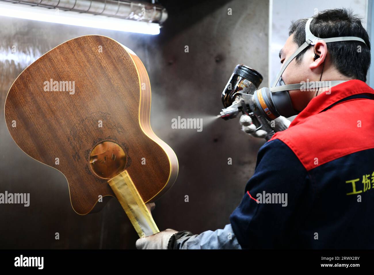 (230921) -- GUIYANG, 21. September 2023 (Xinhua) -- Ein Arbeiter spritzt Farbe auf eine Gitarre in einer Werkstatt des Zheng'an Guitar Culture Industry Park im Kreis Zheng'an, Provinz Guizhou im Südwesten Chinas, 25. März 2020. Nach mehr als 200 aufwändigen und langwierigen Herstellungsverfahren kommen exquisit gefertigte Gitarren als charakteristische Produkte des Zheng'an County in der südwestlichen chinesischen Provinz Guizhou heraus. Diese Kunstwerke werden dann über die China-Europa-Güterzüge, den Wassertransport und andere Mittel in die Welt verteilt. UM MIT "Economic Watch: Chinesische Gitarrenindustrie reitet auf wa Stockfoto