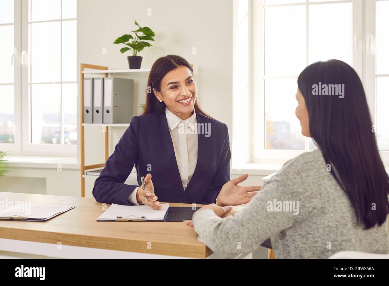 Lächelnde Geschäftsfrau, die mit dem Kunden während eines formellen Meetings im Büro spricht Stockfoto