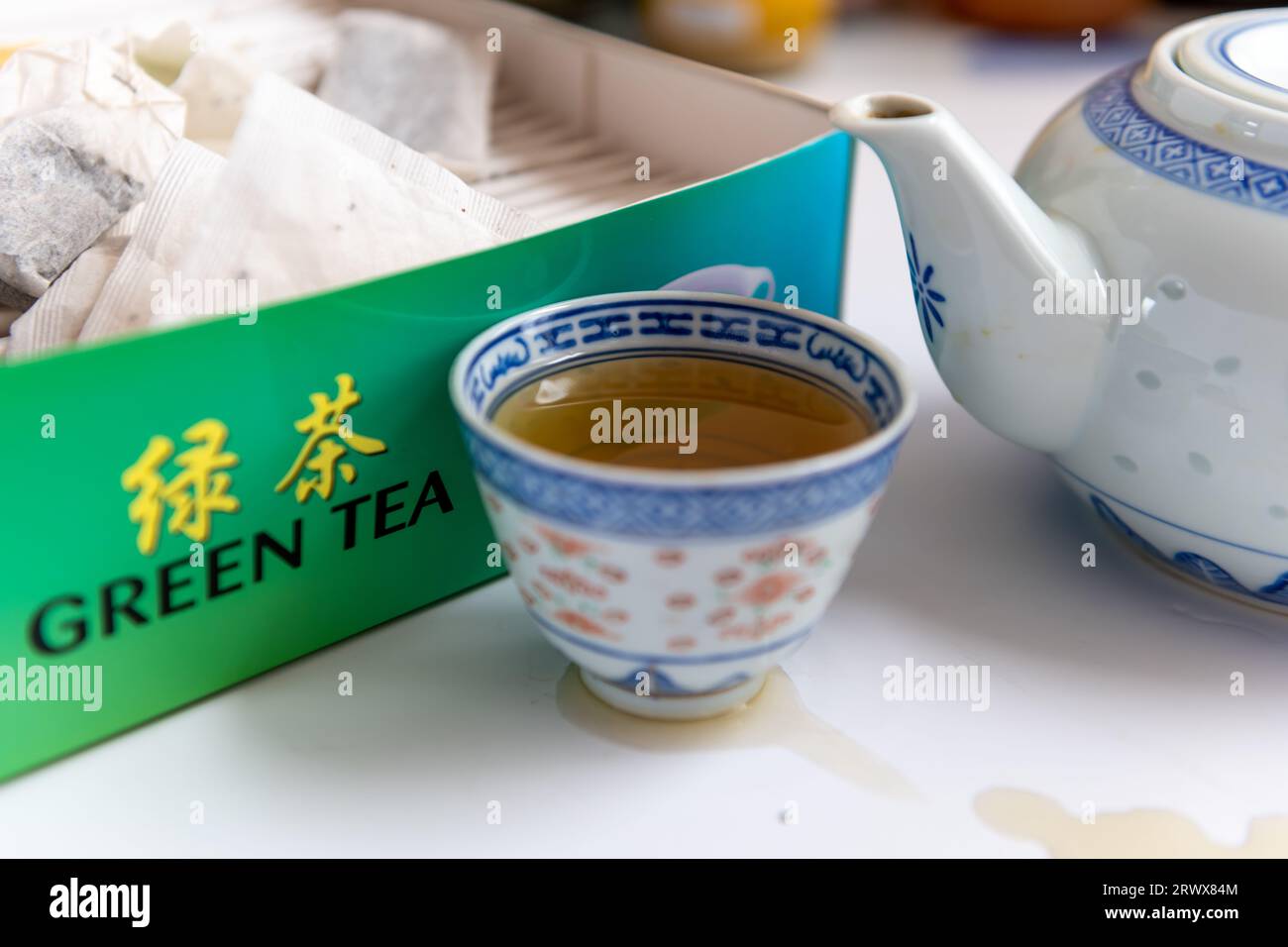 Eine Tasse grüner Tee und eine Teekanne neben einer Schachtel Teebeuteln in weiß. Gesundes Getränk, Lifestyle-Konzept. Stockfoto