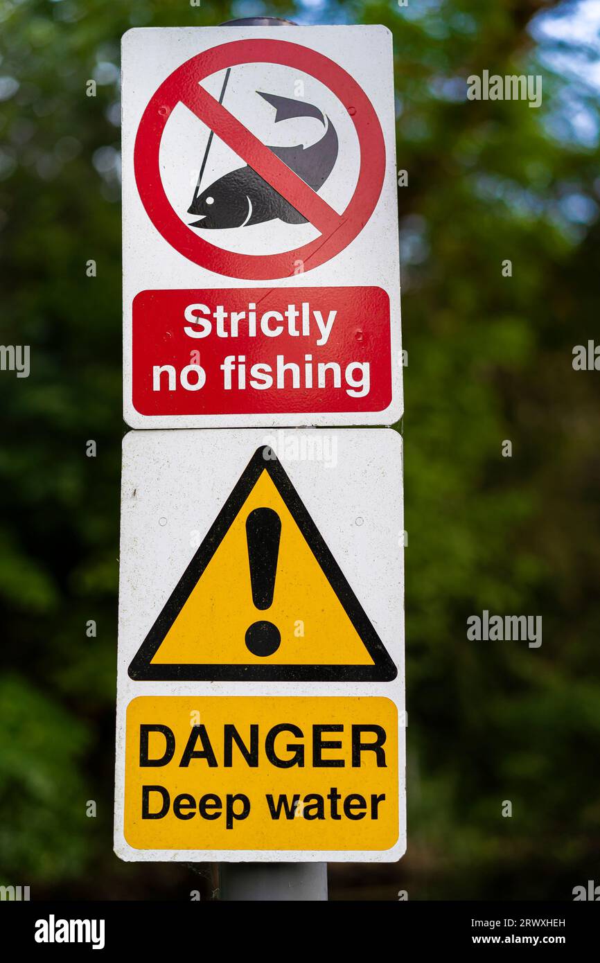 Strikt kein Angelschild auf einem Pfosten zusammen mit einem Danger Deep Water Schild, am offenen See in Großbritannien auf dem Land. Stockfoto