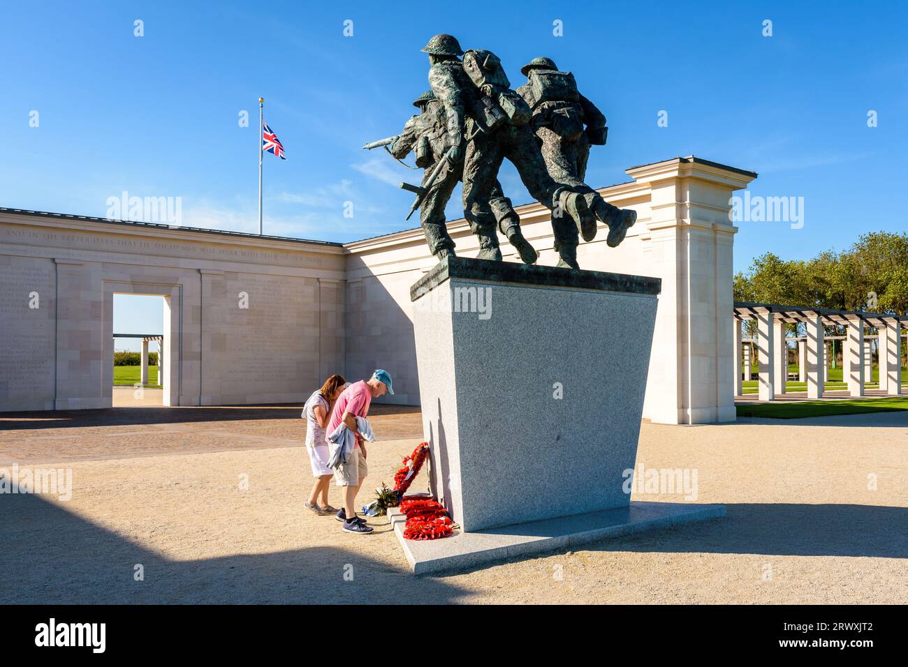 Touristen am Fuße der „D-Day Sculpture“ im British Normandy Memorial, Frankreich, gewidmet britischen Soldaten, die bei den Landungen in der Normandie getötet wurden. Stockfoto