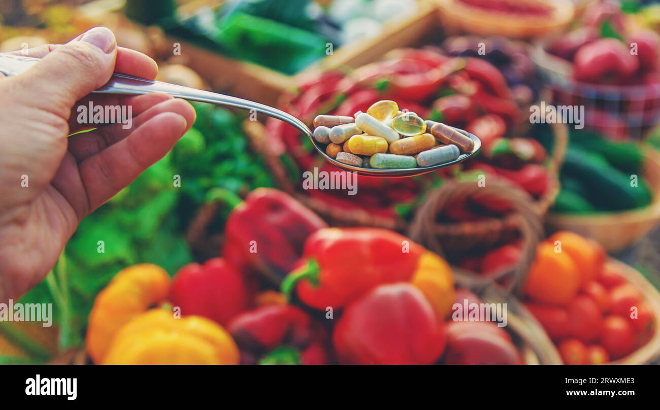 Vitamine und Nahrungsergänzungsmittel in einem Löffel mit Gemüse. Selektiver Fokus. Essen. Stockfoto