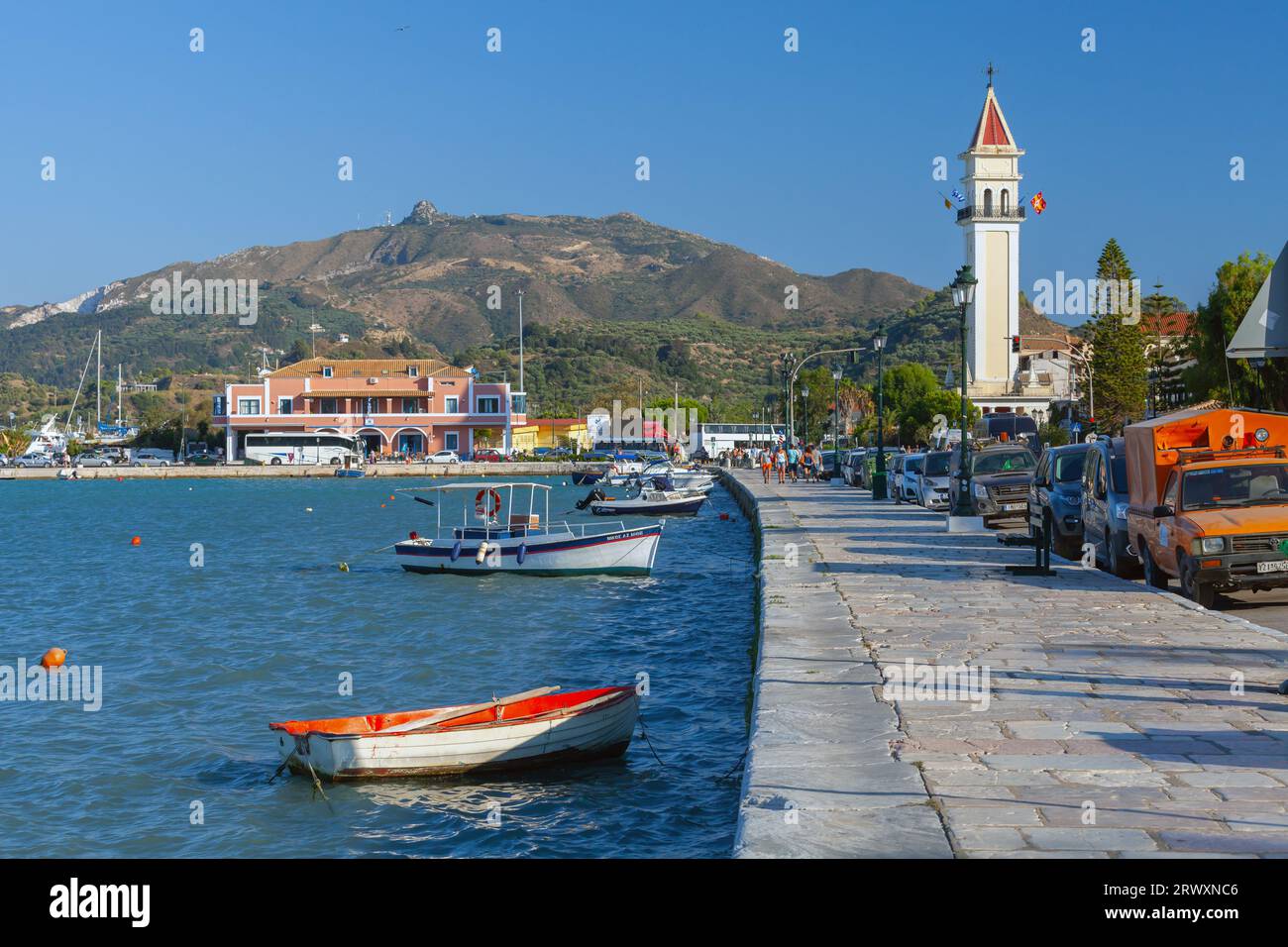 Zakynthos, Griechenland - 14. August 2016: Die Menschen laufen an der Küste des Hafens von Zante in der Nähe von angelegten kleinen Fischerbooten Stockfoto