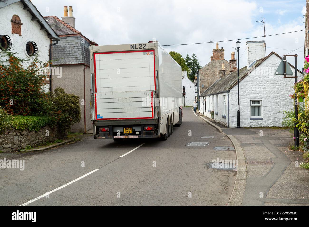 Ein Lkw, der durch die enge Dorfstraße von New Abbey in Dumfries, Schottland fährt Stockfoto