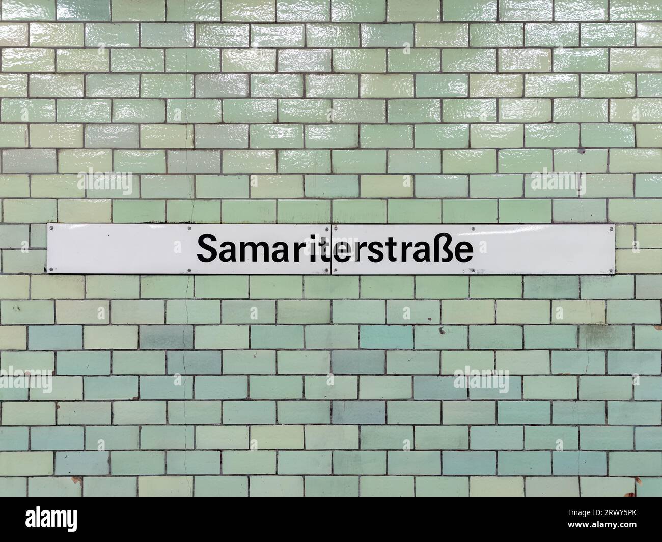 Namensschild des Bahnhofs Samariterstraße der Linie U5 in Berlin. Der Straßenname ist an einer gekachelten Wand in der U-Bahn montiert - öffentliche Verkehrsmittel. Stockfoto