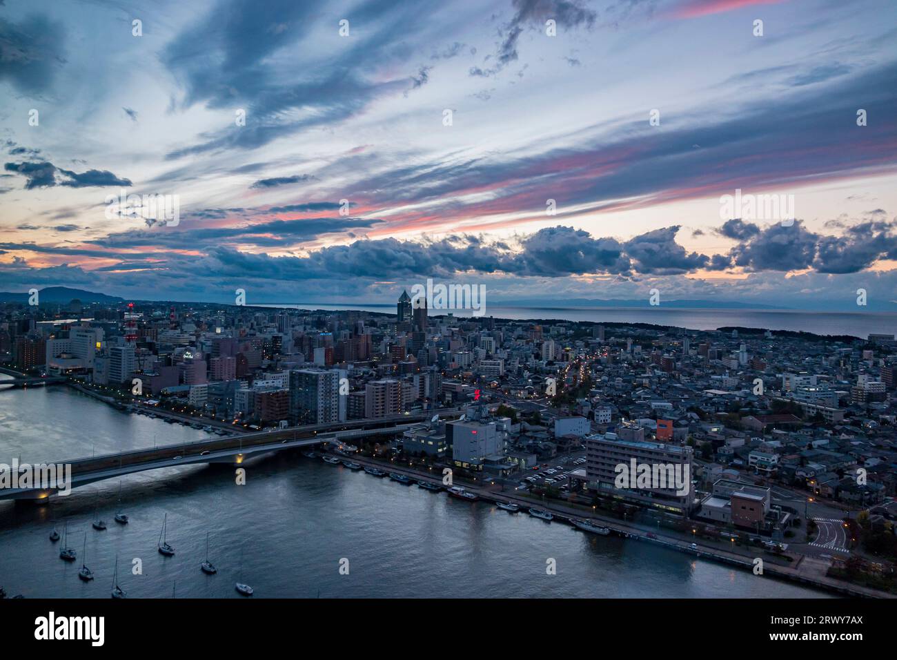 Niigata Stadt in der Abenddämmerung mit Sado Island vor der Küste Stockfoto