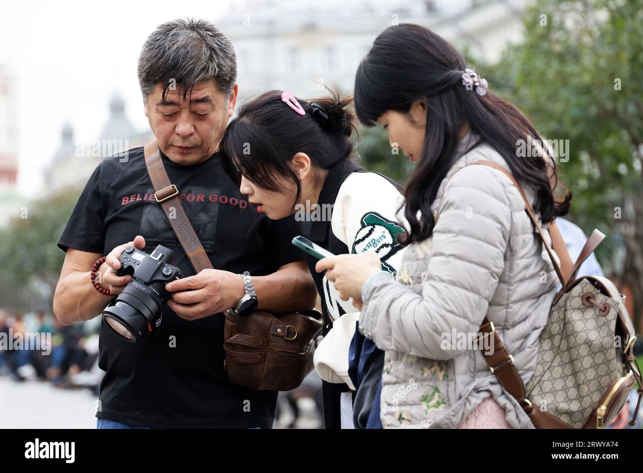Chinesische Touristen, die sich Fotos ansehen, die mit der Kamera aufgenommen wurden. Touristen in Herbststadt Stockfoto