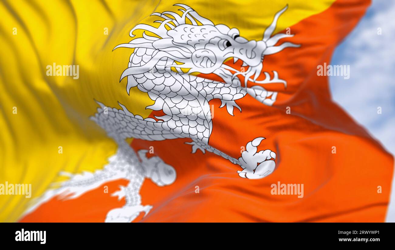 Nahaufnahme der bhutanischen Nationalflagge, die im Wind winkt. Gelbes oberes Dreieck und orangefarbenes unteres Dreieck mit einem weißen Drachen, der Juwelen in der Mitte hält Stockfoto