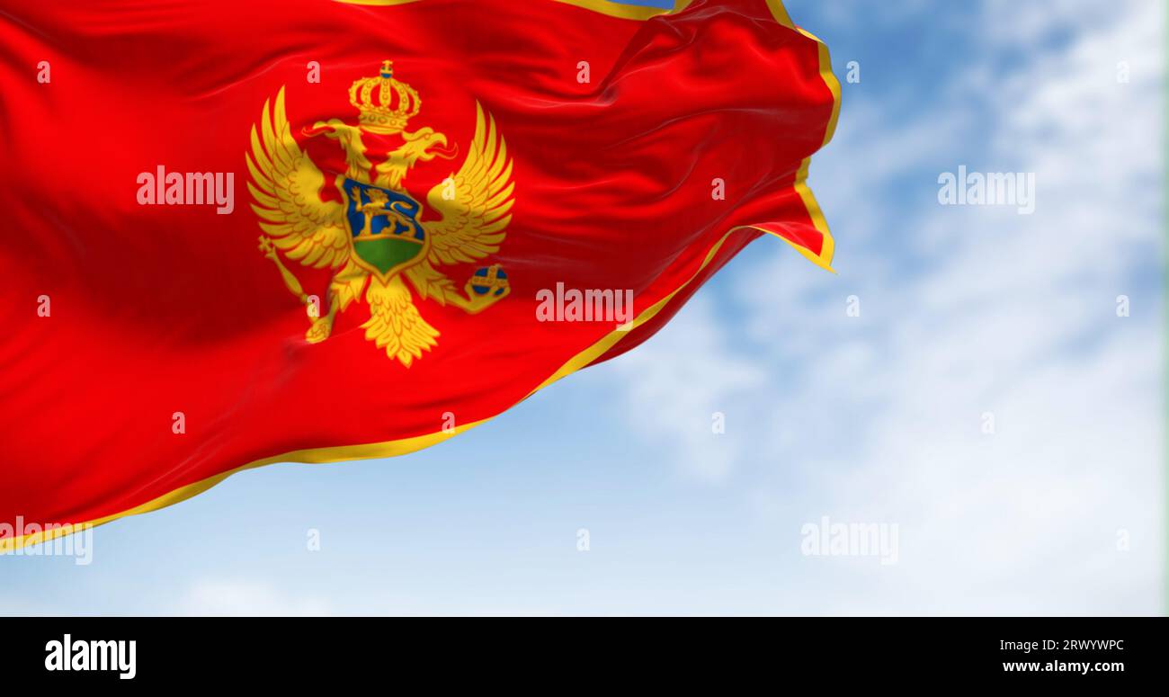 Die Nationalflagge Montenegros winkt an klaren Tagen im Wind. Rot mit goldenem Rand und in der Mitte befindet sich das Nationalwappen. 3D illus Stockfoto