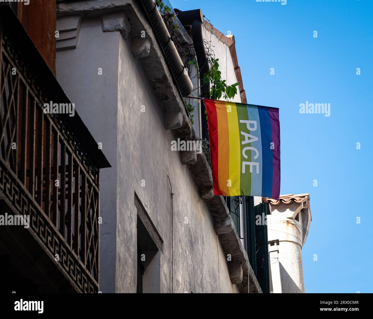 Foto eines Regenbogens PACE oder einer Friedensflagge, die hoch von einem Gebäude in Venedig hängt. Die PACE-Flagge wurde erstmals in Italien bei einem friedensmarsch 1961 verwendet. Stockfoto