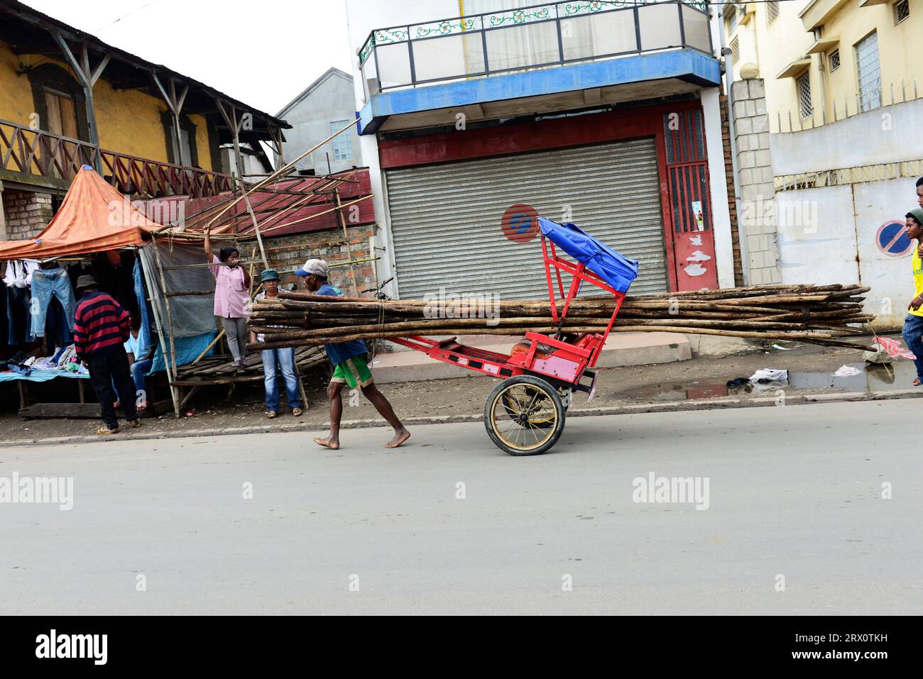 Ein madagassischer Mann, der Holz mit seinem Pousse in Moramanga, Madagaskar, transportiert. Stockfoto