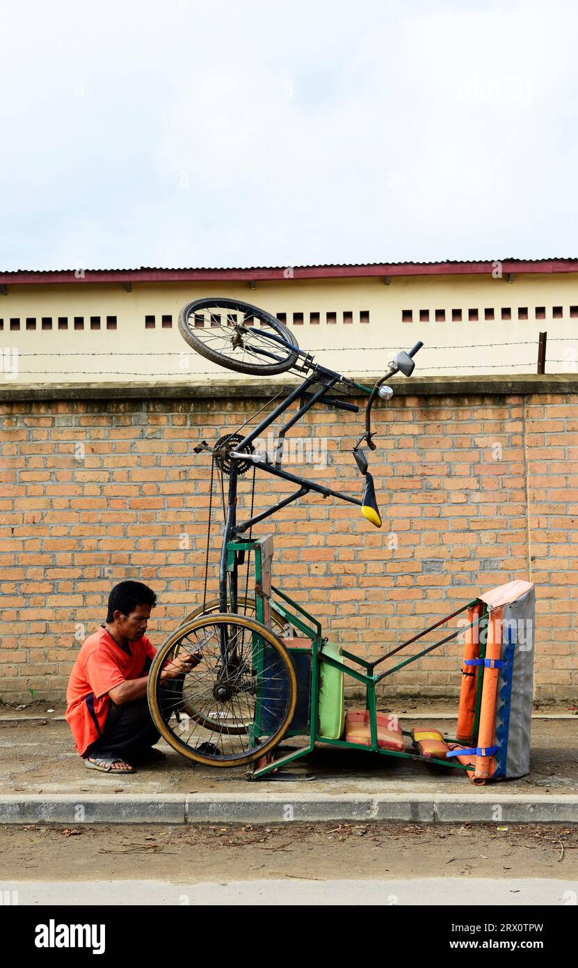 Ein madagassischer Mann, der seine Fahrrad-Rikscha in Moramanga, Madagaskar repariert. Stockfoto