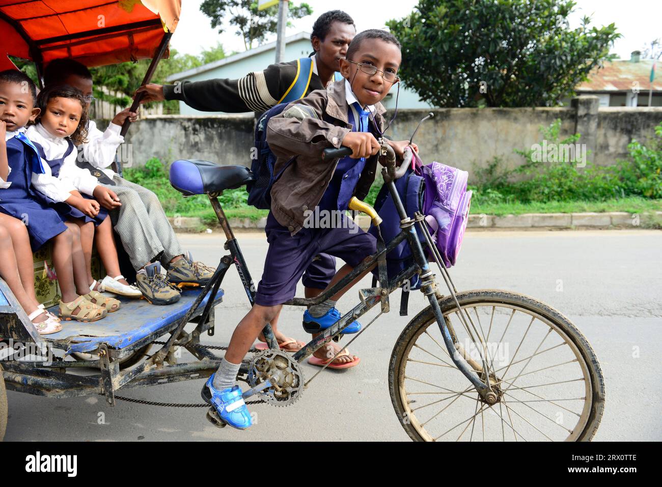 Madagassische Grundschulkinder, die in einer Radfahrrikscha in Moramanga, Madagaskar, zur Schule gehen. Stockfoto